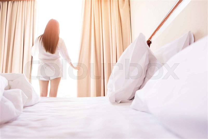 Healthy Woman stretching in bed room and open the curtains after wake up, back view, lifestyle people in cozy indoor comfortable relaxing space, stock photo