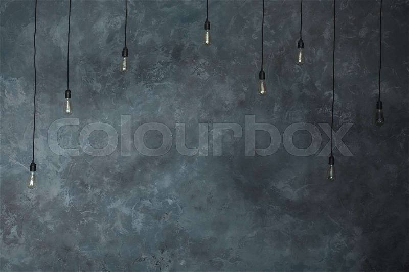 Light bulbs lamps on gray wall of plaster background. Loft Horizontal texture. Vintage wall in the room interior made of the old wall. Grungy wide, copy space, stock photo