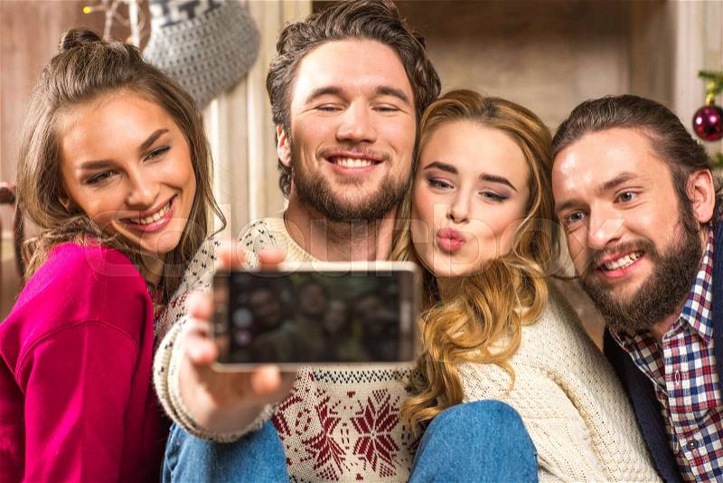 Happy young people taking selfie at christmastime, stock photo