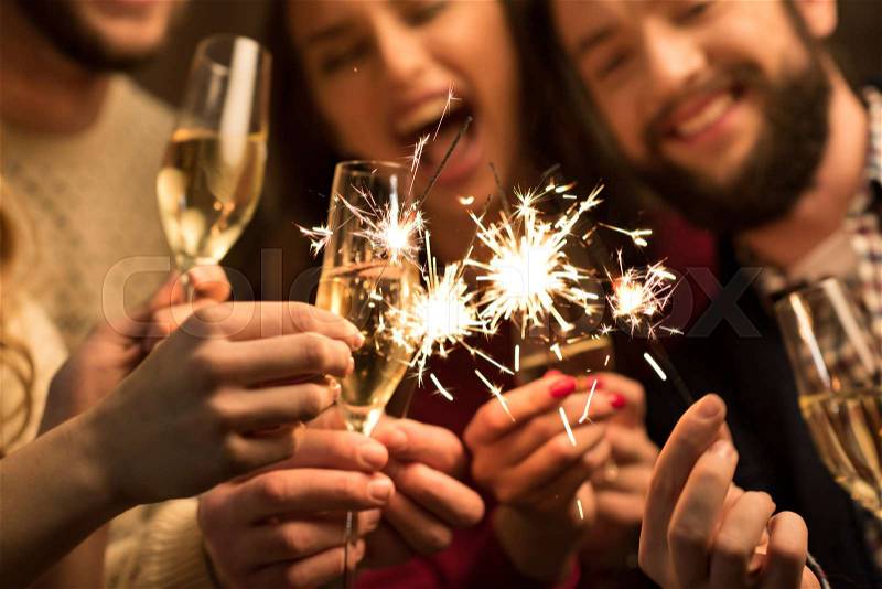 Close-up view of happy people with glasses of champagne and sparklers , stock photo