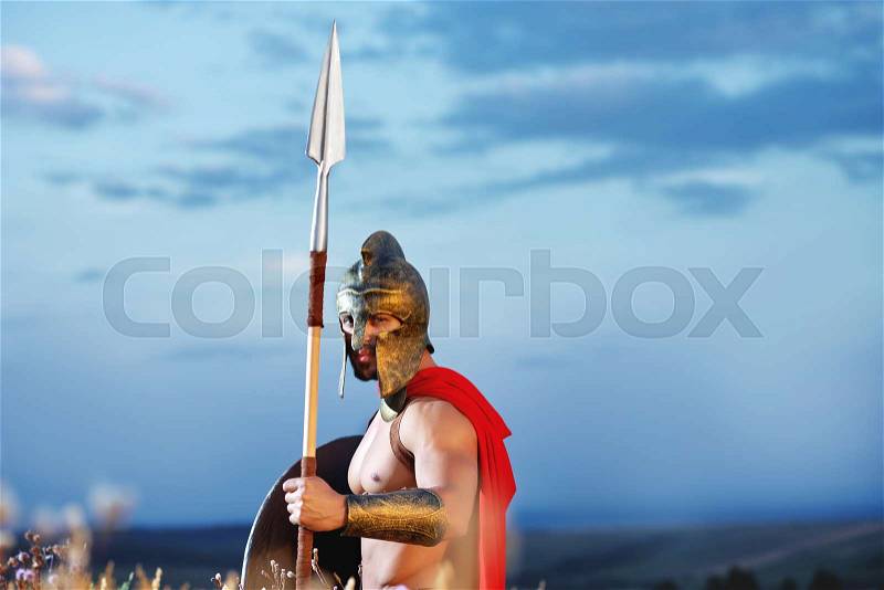 Lonely fighter. Legionary warrior in a helmet and battledress standing alone holding a shield and a spear beautiful skyline on the background copyspace bravery masculinity fearless fighter costume, stock photo