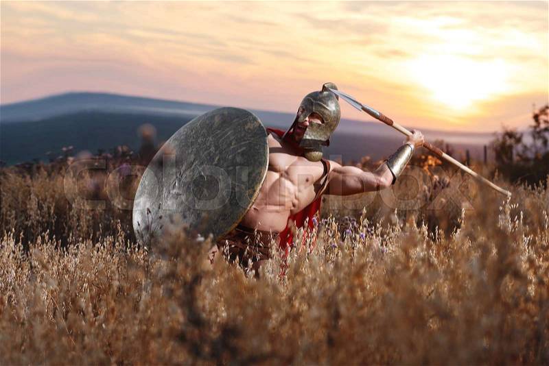 War thunder. Epic shot of a medieval roman warrior in battledress throwing his spear in attack on the enemy stunning dusk landscape on the background defense protection fighter power strength victory, stock photo