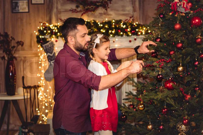 Smiling father and daughter decorating christmas tree, stock photo