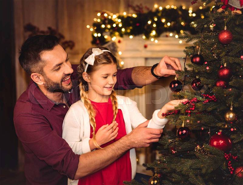 Smiling father and daughter decorating christmas tree , stock photo