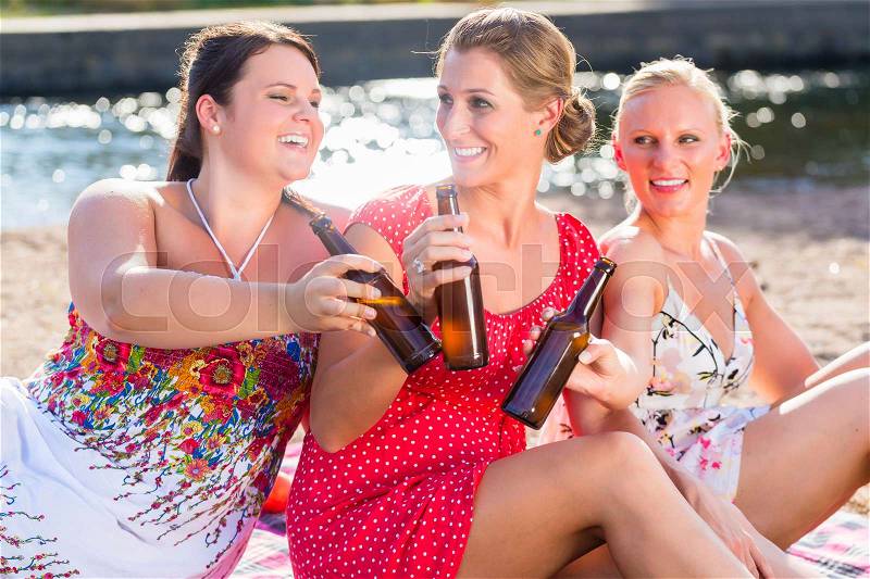 Friends drinking beer at river beach, stock photo