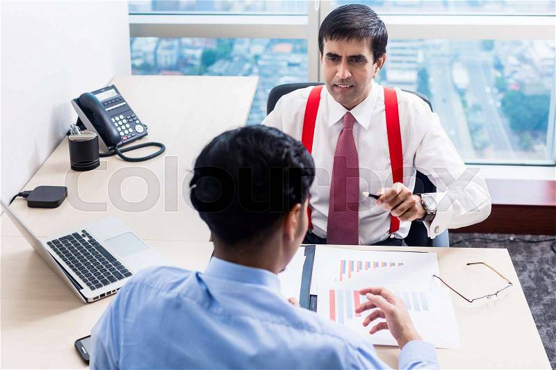 Indian business supervisor talks to subordinate junior professional in office building, stock photo