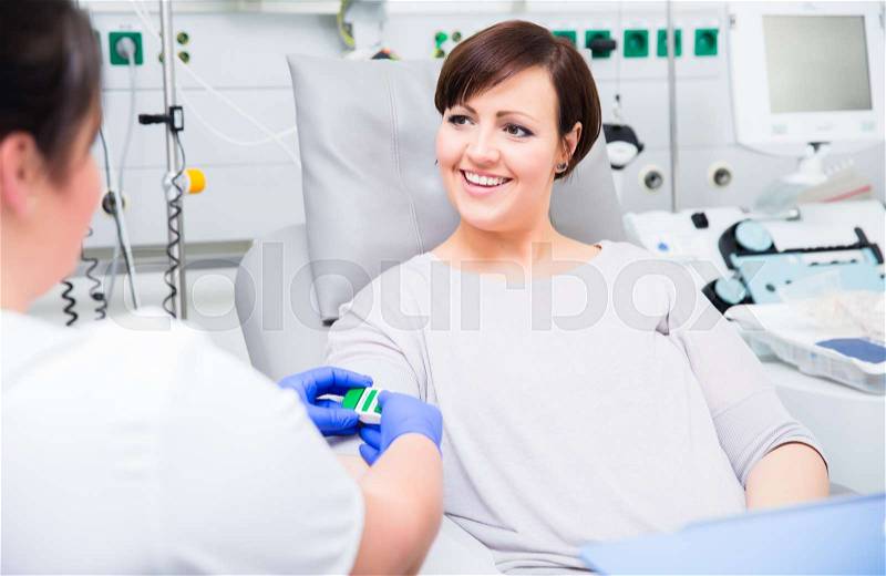 Nurse in hospital checking access at woman blood donor, stock photo