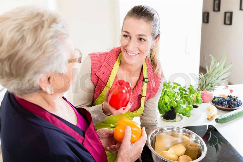 Mother in law explaining correct use of bell pepper in kitchen to her daughter in law once again, stock photo