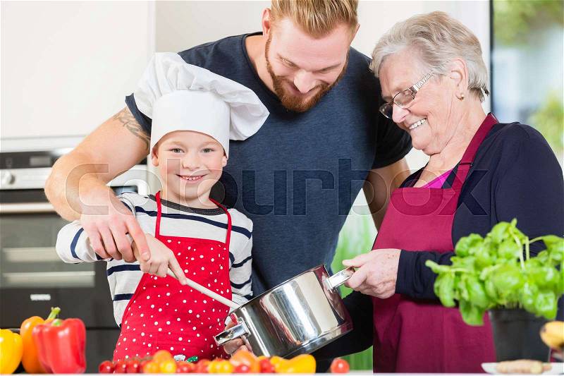Mom, dad, granny and grandson together in kitchen preparing food, stock photo