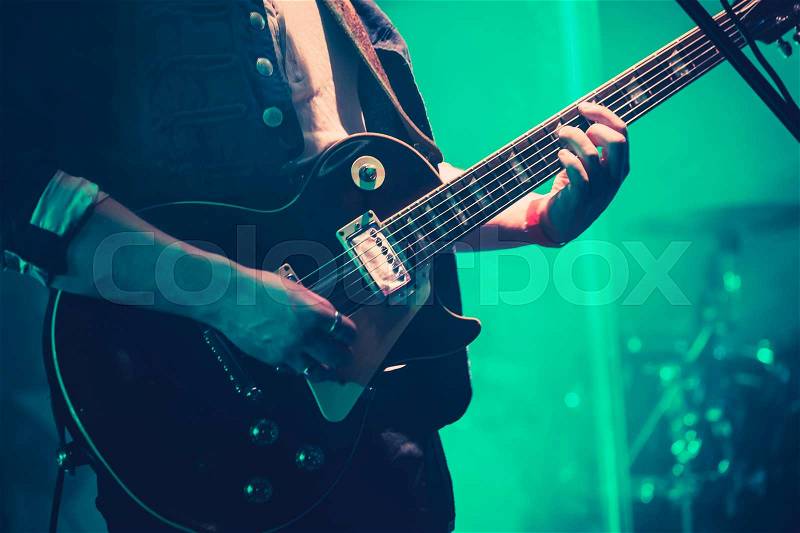 Electric guitar player on a stage in green lights, soft selective focus, stock photo