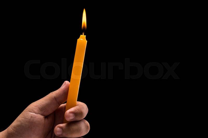 Close up hand holding light burning candle. Studio shot isolated on black background, stock photo