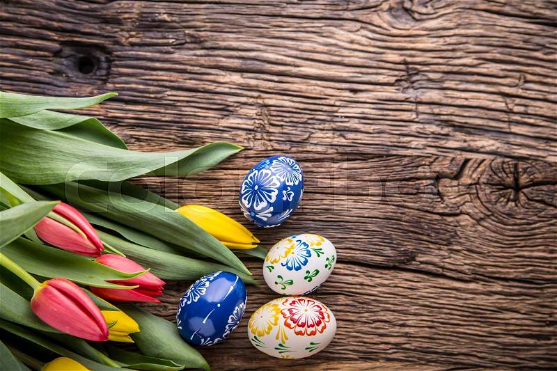 Easter. Hand made easter eggs and spring tulips on old wooden table, stock photo