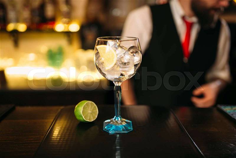 Attractive cocktail and lime on wooden counter. Advertising of alcoholic beverages , stock photo