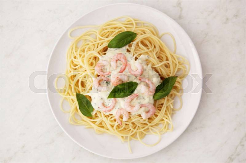 Spaghetti with white sauce and shrimps on a white plate, stock photo