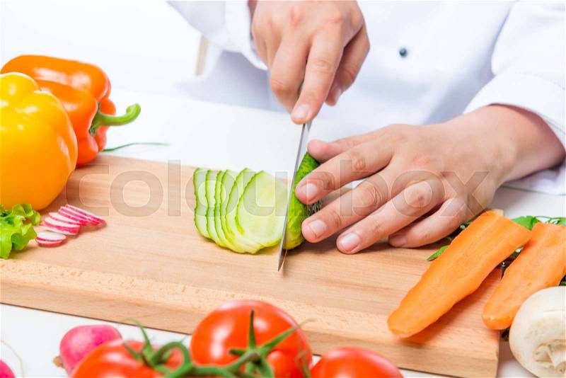Chef cuts the cucumber salad carefully on a wooden cutting board, stock photo