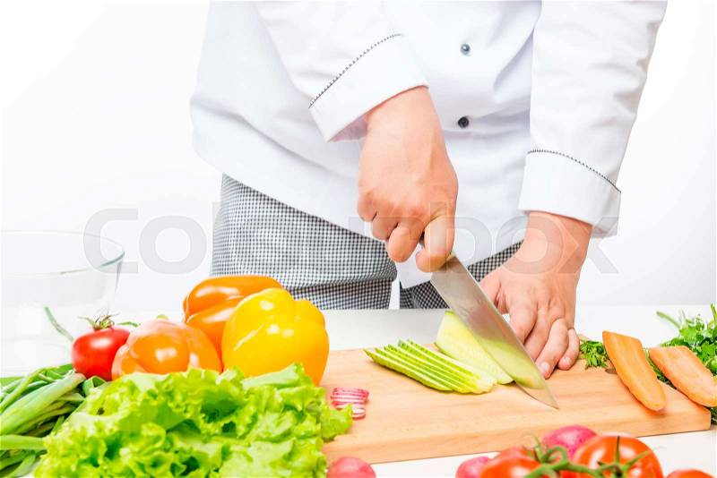 Chef cuts salad, prepares fresh vegetables on white background, stock photo