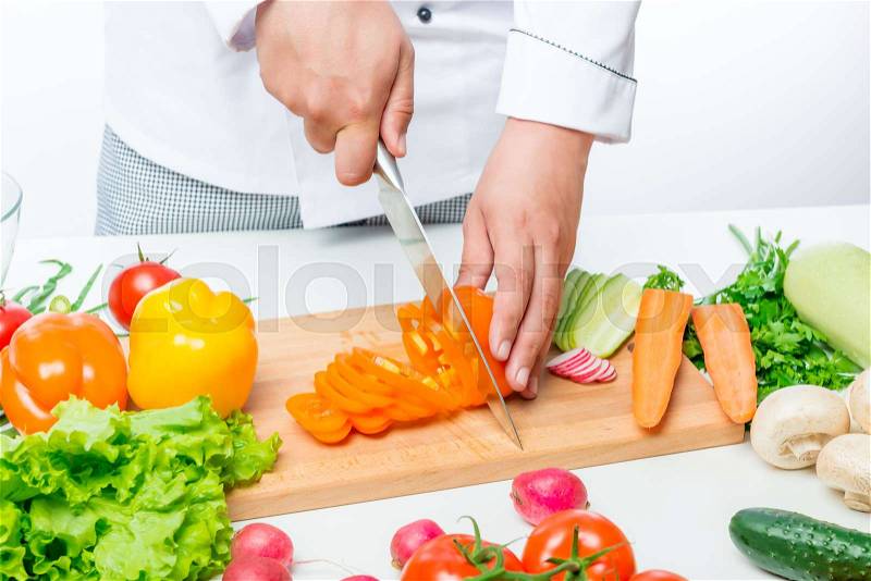 Chef cuts carefully sweet orange peppers for a vegetable salad, stock photo