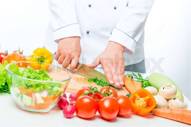 Chef cuts the different vegetables in a bowl for the salad, close up hands, stock photo