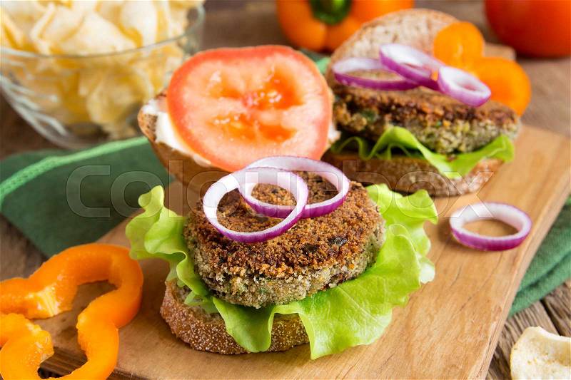 Vegetarian lentil burger with vegetables on wooden cutting board - healthy vegan organic vegetarian diet fast food burger lunch, stock photo