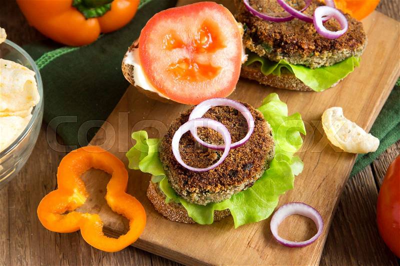 Vegetarian lentil burger with vegetables on wooden cutting board - healthy vegan organic vegetarian diet fast food burger lunch, stock photo