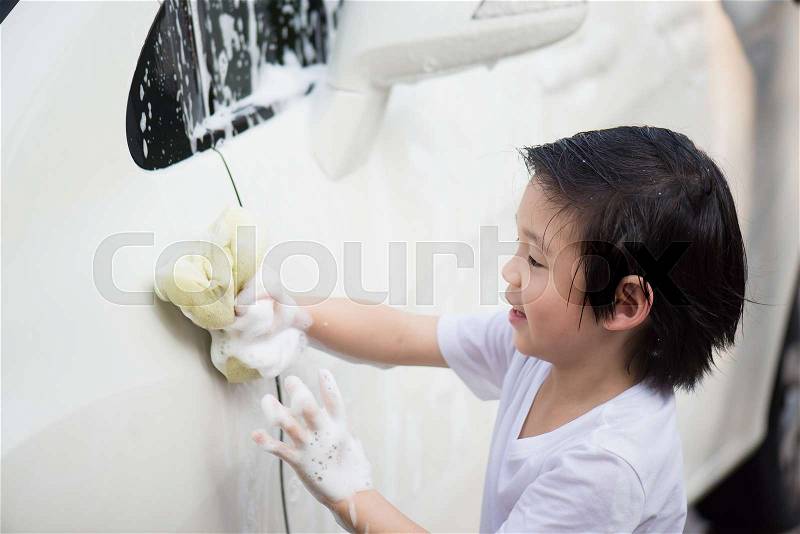 Asian child washing car in the garden on summer day, stock photo