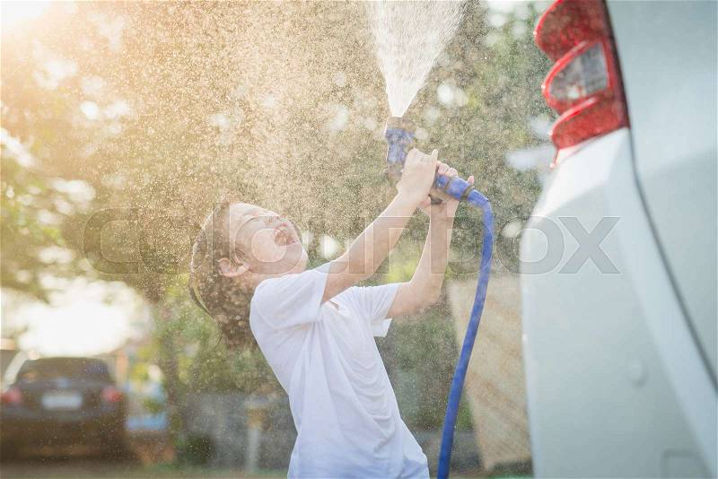 Asian child washing car in the garden on summer day, stock photo