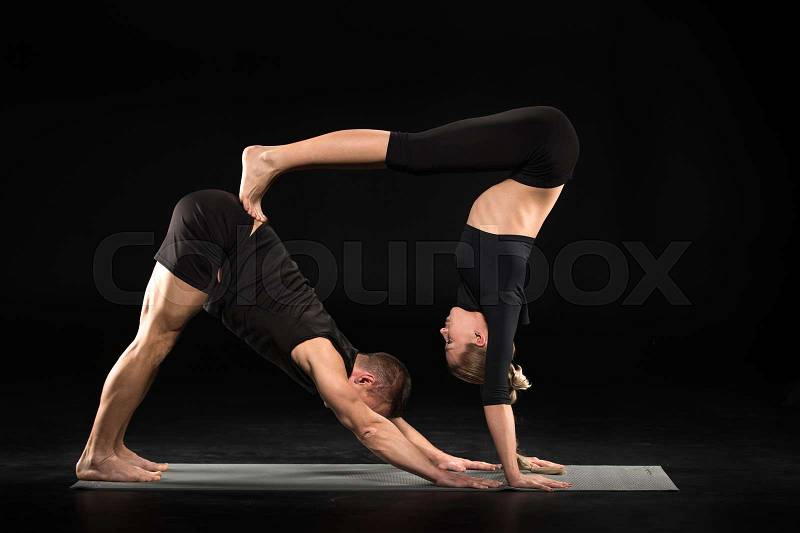 Couple performing acroyoga double down dog pose on yoga mat , stock photo