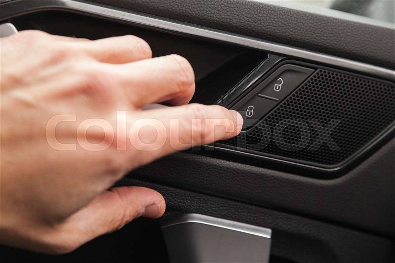 Driver hand pushes door lockers button of luxury crossover car. Close up photo with selective focus, stock photo