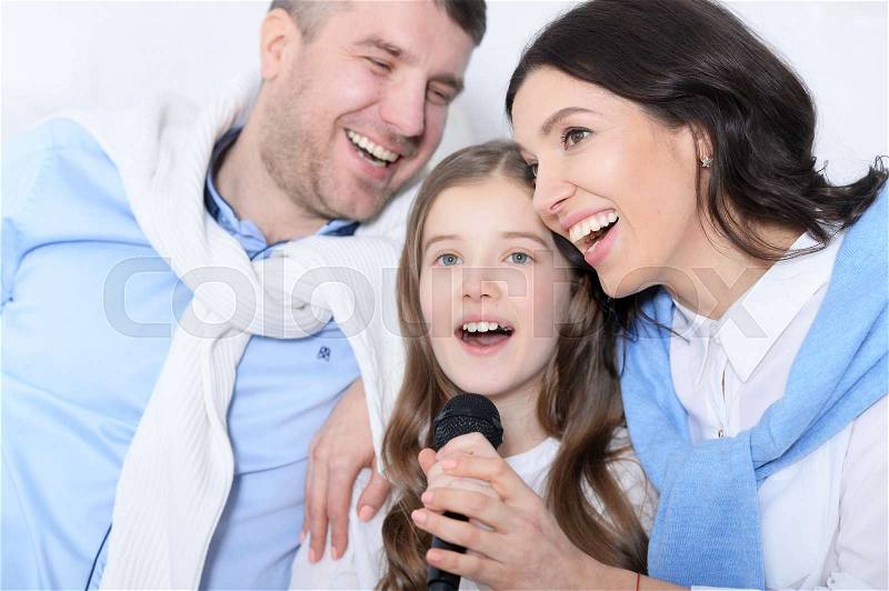 Portrait of a family with daughter singing karaoke, stock photo
