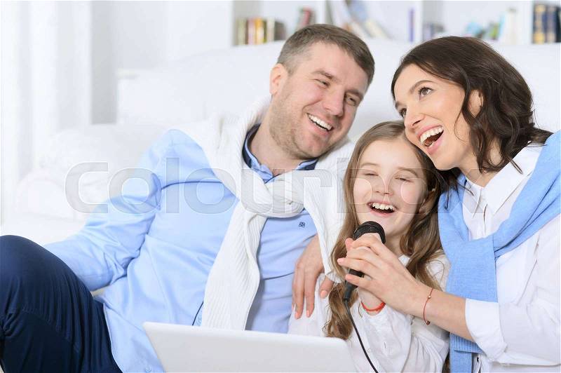 Portrait of a family with daughter singing karaoke, stock photo
