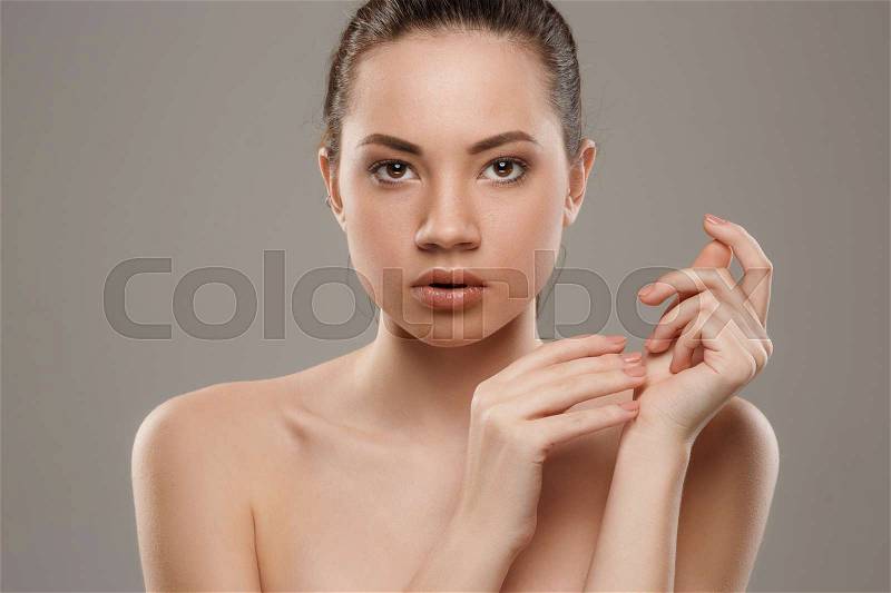The beautiful female face. The perfect and clean skin of face on gray, stock photo