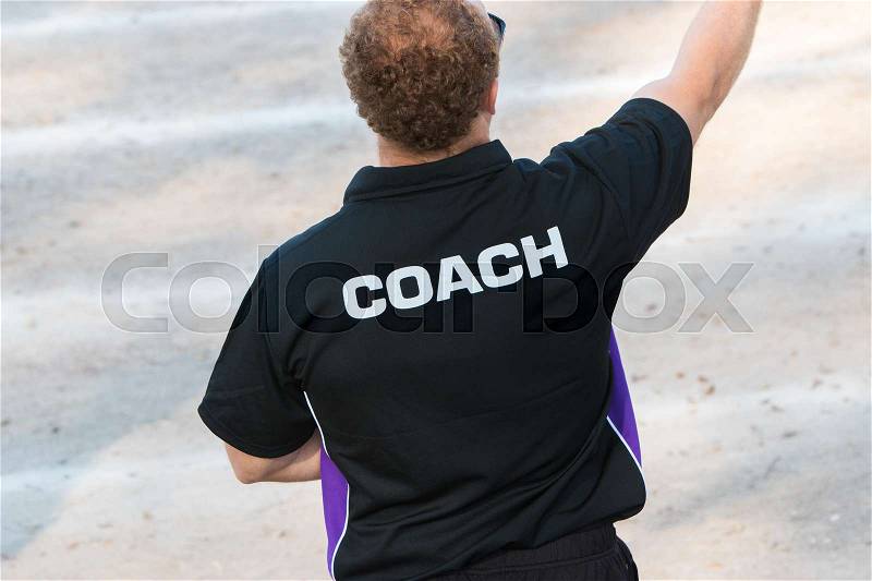 Back of a coach\'s black shirt with the white word Coach written on it, stock photo