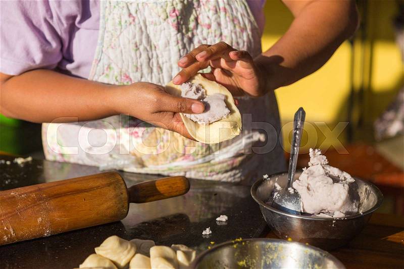 Woman making curry puff, adding stuffing in the dough, stock photo