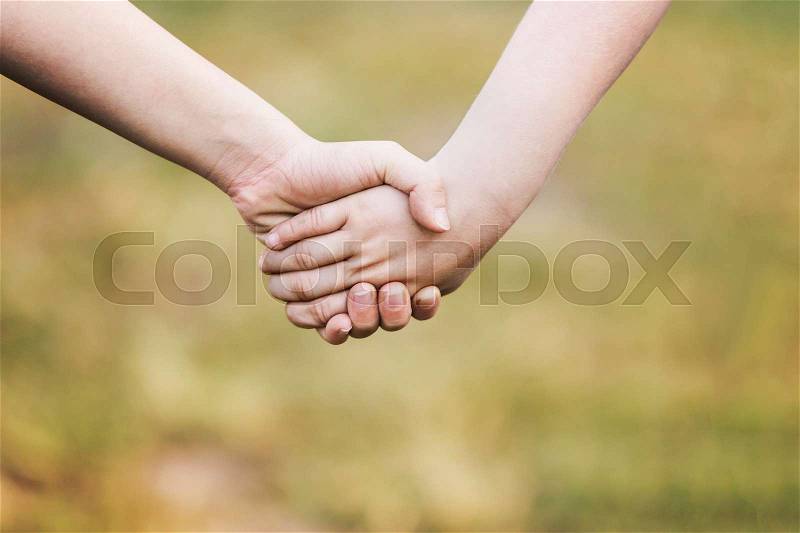 Kids\' hands holding for support and friendship, outdoor with blur green grass background, stock photo