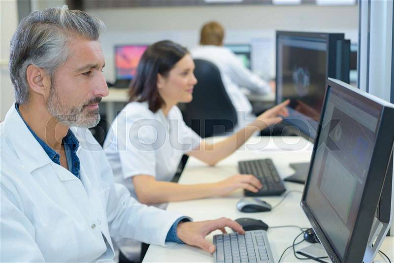 Team of medical analysts working on computers, stock photo