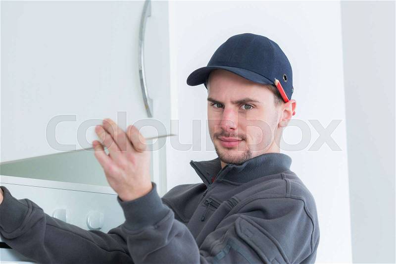 Man fitting kitchen cupboard, stock photo