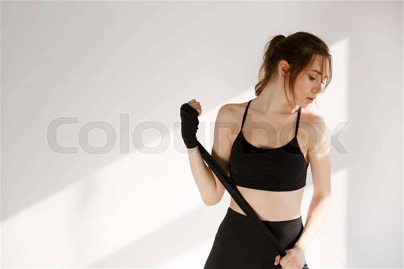 Portrait of a female kick boxer wearing hand bandage against white background, stock photo
