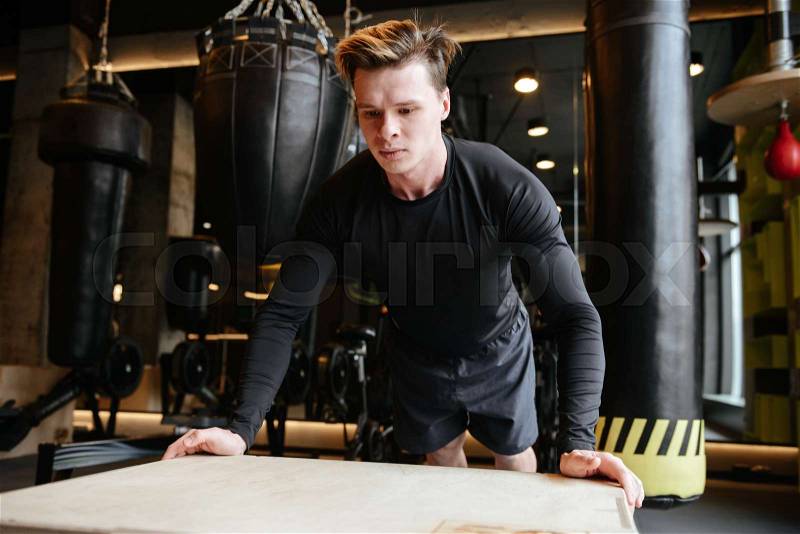 Athletic man which push-ups on box in gym, stock photo