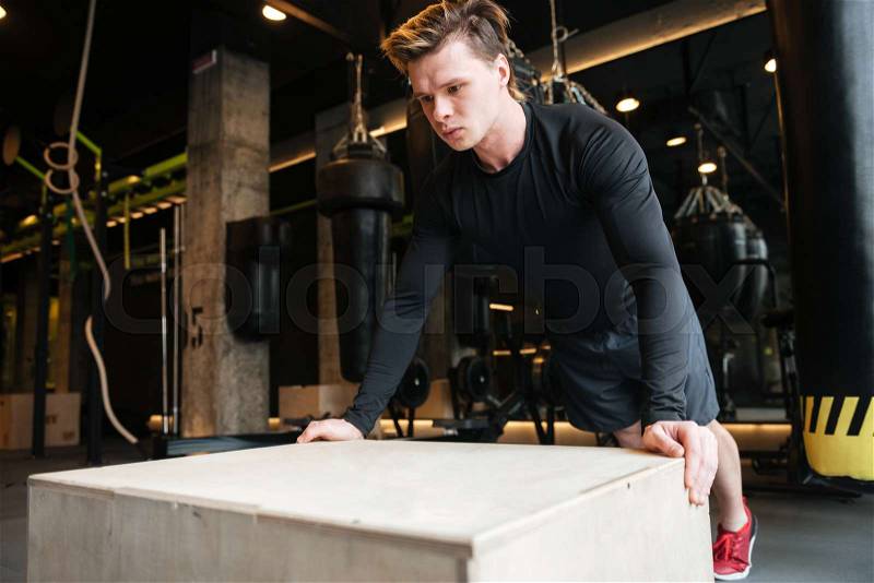 Side view of Athletic man which push-ups on box in gym, stock photo