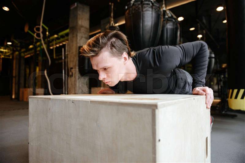 Young Athletic man which push-ups on box in gym, stock photo