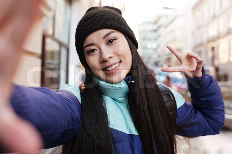 Asian woman in warm clothes which making selfie on the street, stock photo