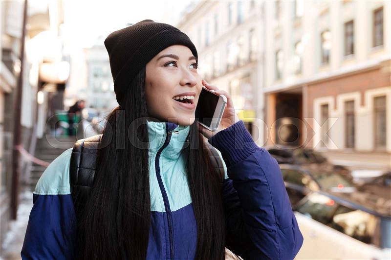 Asian woman in warm clothes which talking on the her phone on the street and looking away, stock photo