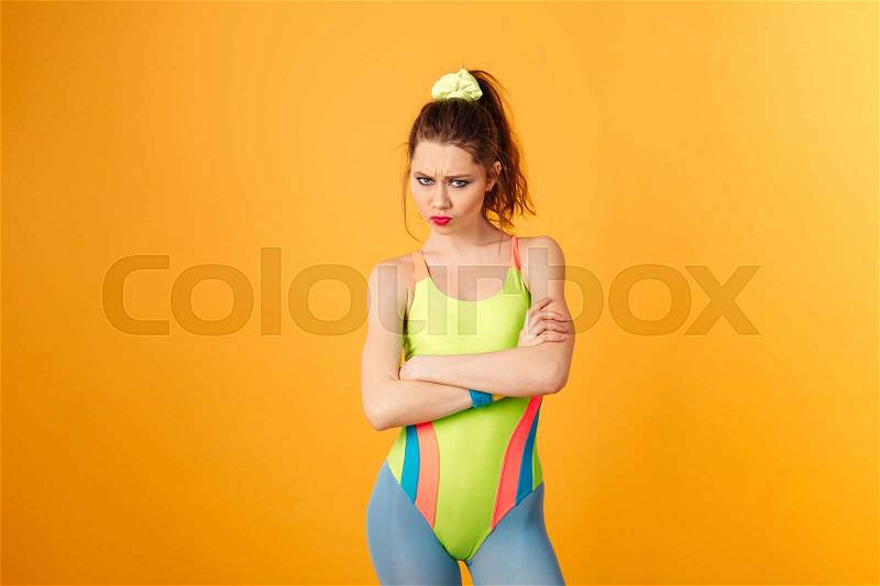 Sad frowning young woman athlete standing with arms crossed, stock photo