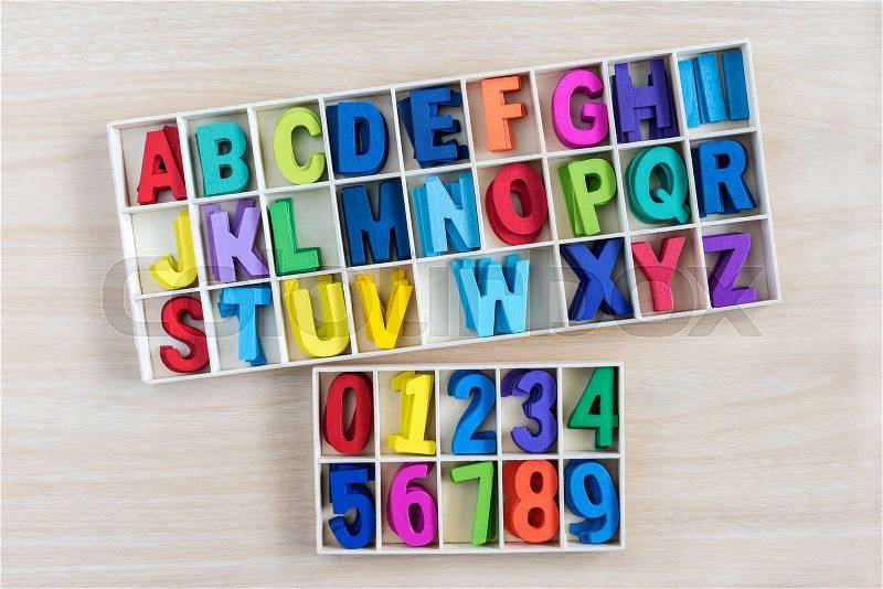 Colorful alphabet letters and number in a wooden box with square compartments for teaching kids to read and spell, overhead viewful , stock photo