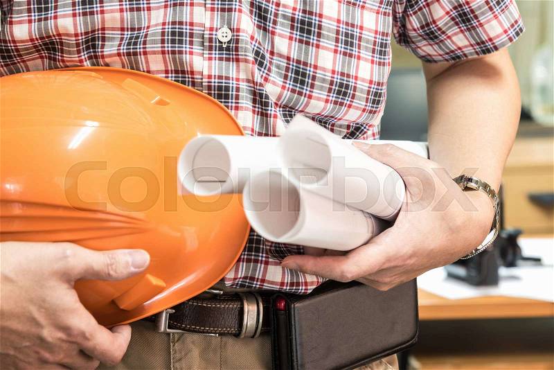 Young architect holding blueprint and hamlet in office renovation, architecture contractor developer and renovation concept, stock photo