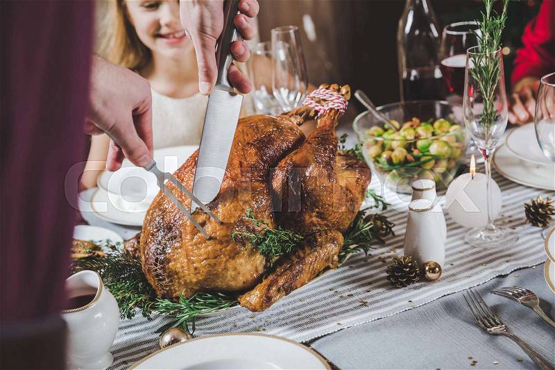 Partial view of man carving roasted turkey at table served for Christmas , stock photo