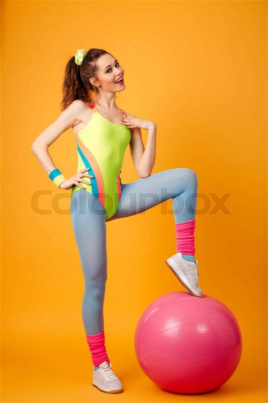 Photo of attractive young fitness lady posing over yellow background. Looking at camera, stock photo