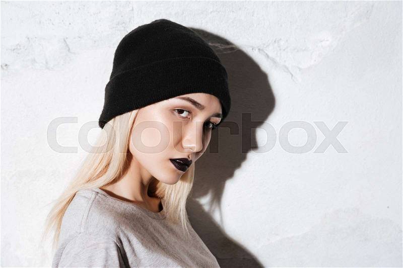 Side view of Young Hipster in black hat looking at camera, stock photo