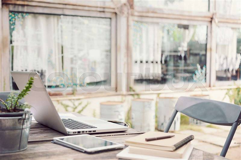 Outdoor work table with laptop computer, tablet, phone, and other stationery in selective focus on computer screen, vintage tone, stock photo