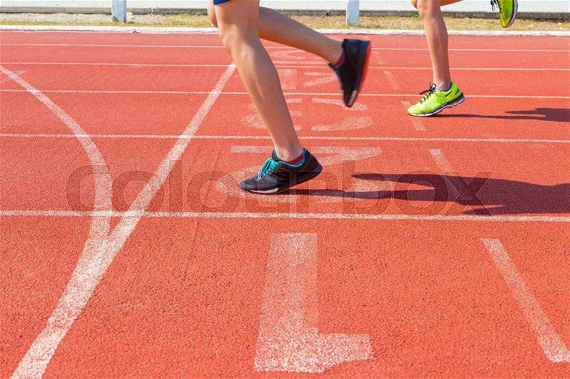 Feet of two female runners running on race track at finish line, stock photo